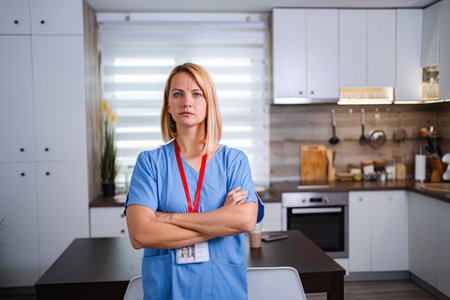 Serious doctor standing in kitchen with arms crossedの写真素材