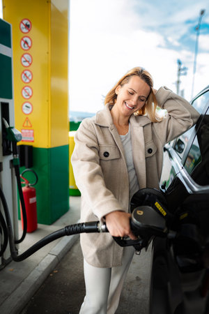 Smiling woman refueling car with diesel at gas stationの写真素材