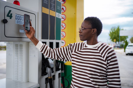 Woman paying for fuel with smartphone at gas stationの写真素材