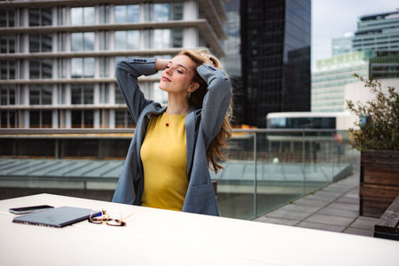 Businesswoman relaxing on city rooftop during work breakの写真素材