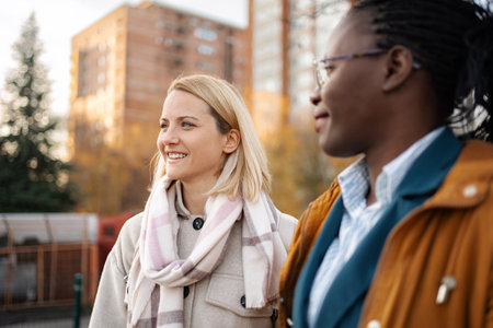 Diverse women friends walking together outdoors smilingの写真素材