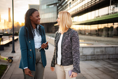Businesswomen walking and communicating outdoors in cityの写真素材