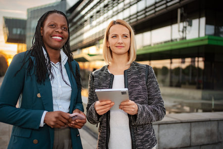 Diverse businesswomen collaborating with technology in city outdoorの写真素材
