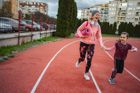Mother and daughter running on track holding hands