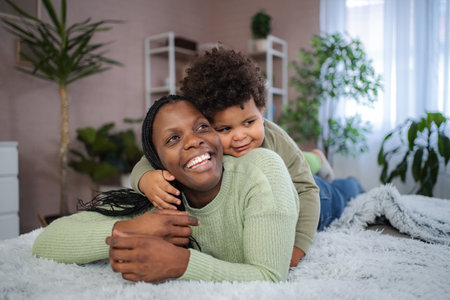 Black mother and child cuddling on the floorの写真素材