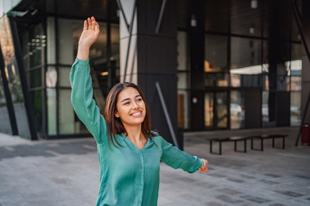 Young businesswoman celebrating success in front of modern office buildingの写真素材