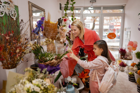 Mother and daughter explore vibrant flower shop, sharing joy and creativity on a sunny afternoonの写真素材