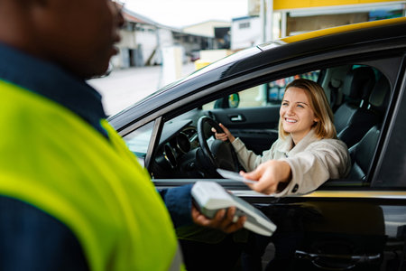 Woman paying for gas fueling car with credit card at service station