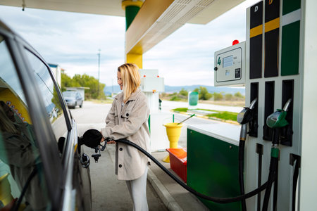 Woman refueling car at gas station, filling up tank