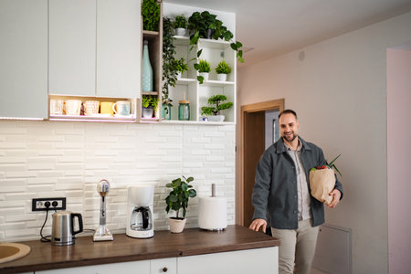 Man arriving home carrying fresh groceries in kitchenの写真素材