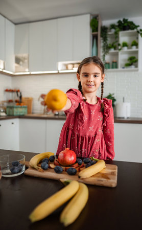 Girl holding lemon offering healthy snack in kitchenの写真素材