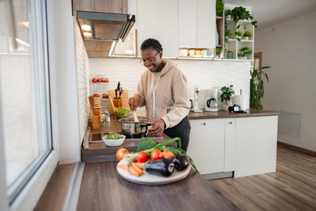 Young adult woman cooking healthy vegetables in modern kitchen