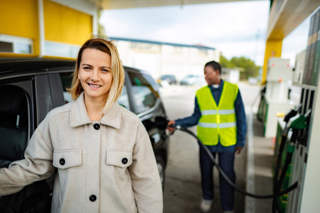 Woman smiling while gas station attendant refueling car
