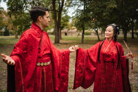Couple celebrating Chinese wedding ceremony holding hands outdoorsの写真素材