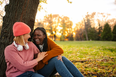 Diverse women friends laughing together enjoying autumn parkの写真素材