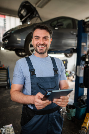Car mechanic using a digital tablet and smiling at the camera inの写真素材