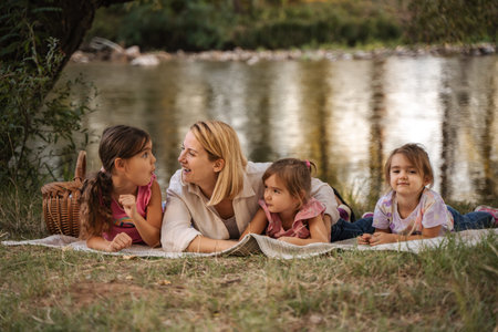 Mother and daughters enjoying a picnic by the riverの写真素材