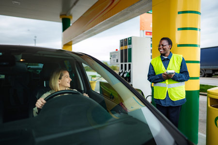 Woman paying for gas at service station to attendantの写真素材