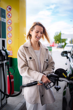 Woman smiling fueling diesel car at gas stationの写真素材