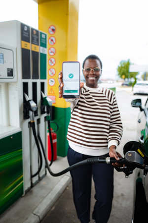 Woman refueling car showing successful mobile payment at gas stationの写真素材