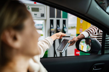 Woman making credit card payment at gas station pumpの写真素材