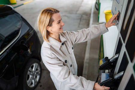 Woman selecting fuel type at gas stationの写真素材