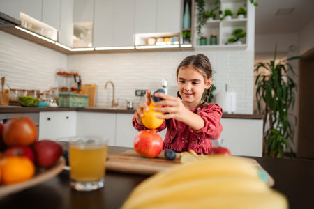 Young girl stacking fresh fruit in modern kitchenの写真素材