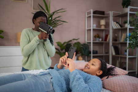 Mother filming daughter using vintage camera and phoneの写真素材