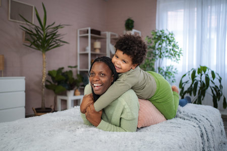 African American mother and child playing on bedの写真素材