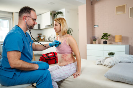 Doctor examining female patient with rash during home visitの写真素材