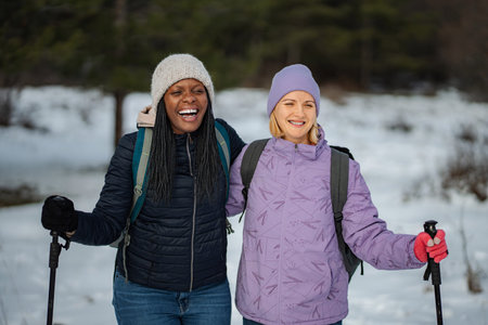 Diverse women friends enjoying winter hiking in snowの写真素材