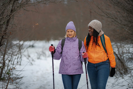 Diverse friends enjoying winter hike with trekking polesの写真素材
