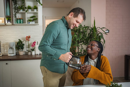 Man pouring coffee for laughing woman in kitchenの写真素材