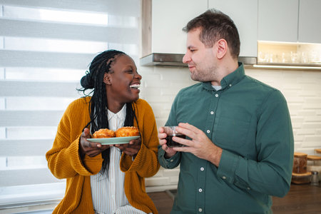 Smiling diverse couple enjoying morning coffee and breakfastの写真素材