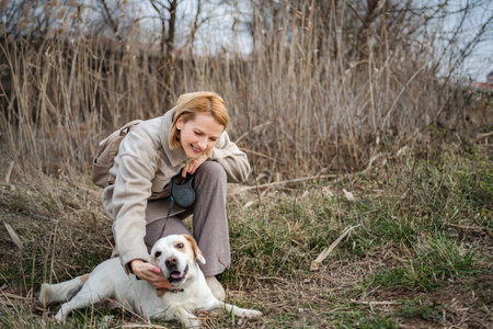 Woman petting happy dog during autumn walk