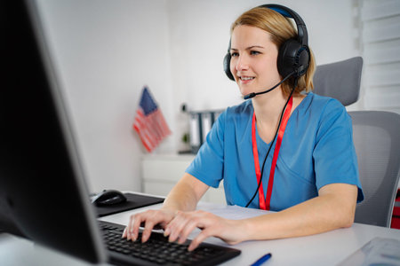 Nurse wearing headset typing on computer for telehealth consultation