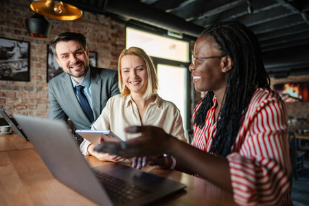 Diverse team collaborating on laptop computer in cafe
