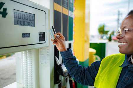 Smiling person paying fuel with credit card at gas station