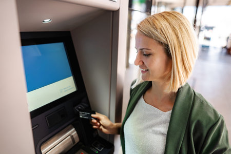 Woman inserting credit card into ATM for banking transaction