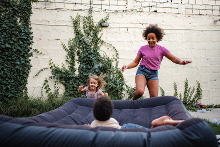 Young adults and children jumping on inflatable mattress