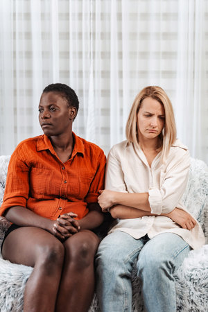 Two Young Women Feeling Sad and Disappointed on Sofaの写真素材