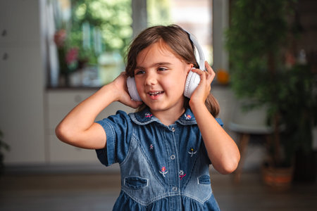 Little girl listening to music with headphones at home