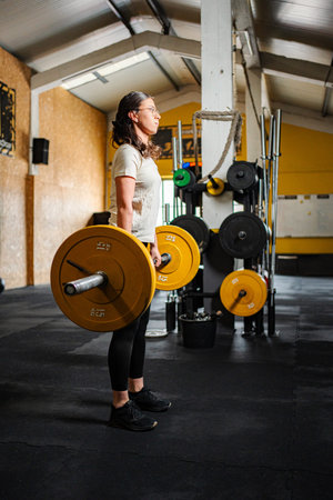 Woman standing with barbell after lifting weights