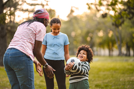 Family playing soccer outdoors with children in park