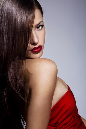 beautiful brunette with red lips and dress, studio portraitの写真素材