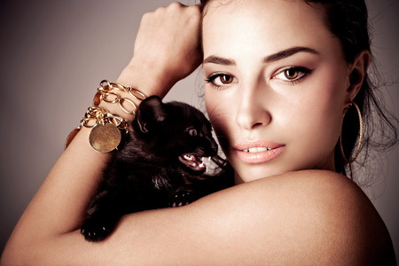 beautiful young woman holding black kitten, studio shotの写真素材
