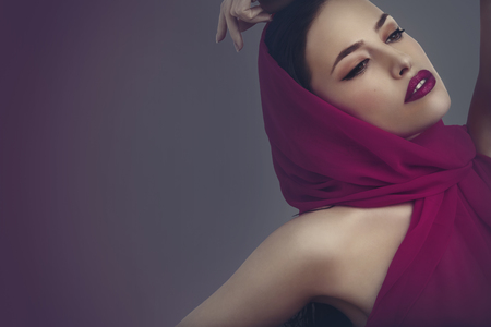 beautiful woman portrait with magenta scarf and makeupの写真素材