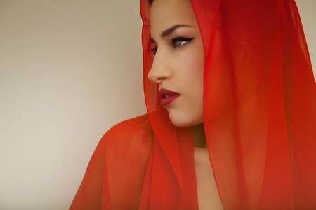 beautiful woman portrait with red lips and red veil over her head, studio shotの写真素材