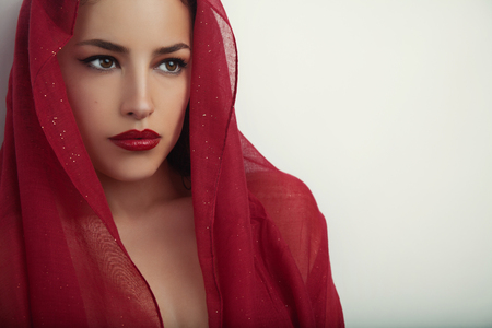 beautiful woman portrait with red lips and red veil over her head, studio shotの写真素材