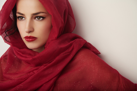 beautiful woman portrait with red lips and red veil over her head, studio shotの写真素材